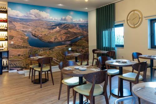 a restaurant with tables and chairs and a mural at Casa Dona Edite Guesthouse Douro in Vilarinho de Cotas