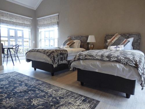 a bedroom with two beds and a rug at Romantic Boutique Cottage in upper Hogsback in Hogsback