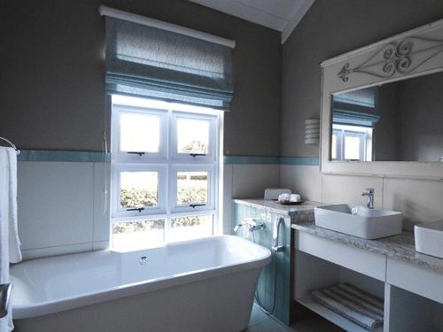 a bathroom with a tub and a sink and a mirror at Romantic Boutique Cottage in upper Hogsback in Hogsback