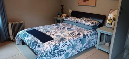 a bedroom with a bed with a blue and white comforter at Anchors Aweigh in Hibberdene