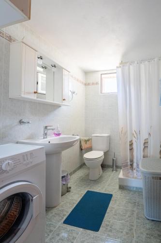 a bathroom with a toilet sink and a washing machine at Zante's Northern View in Koríthion