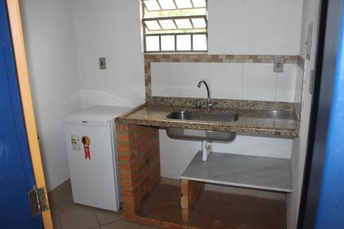 a kitchen with a sink and a small refrigerator at Pousada Serra Azul in Tiradentes