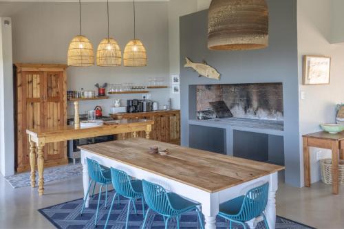 a kitchen with a wooden table and blue chairs at Begha 180 Beach House in Begha Mouth