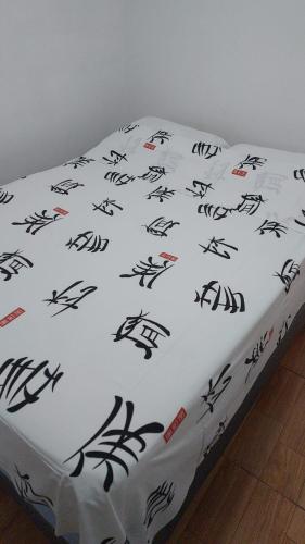 a bed with a white sheet with black drawings on it at Apartamento Indaiatuba in Indaiatuba