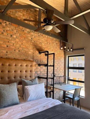 a bedroom with a brick wall and a bed and a ceiling fan at Red Robin Guesthouse in Postmasburg