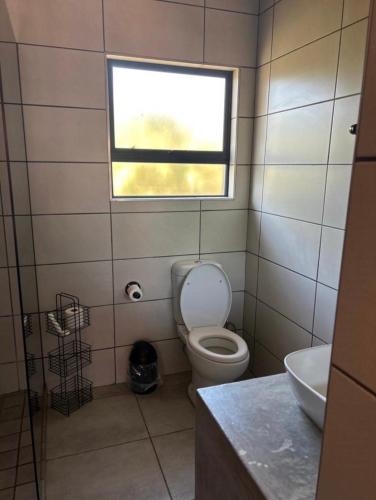a small bathroom with a toilet and a window at Red Robin Guesthouse in Postmasburg