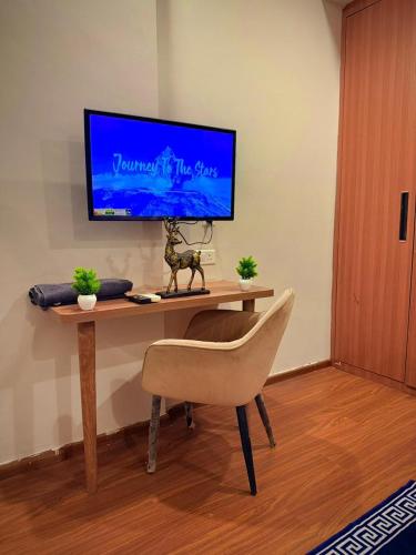 a desk with a chair and a television on a wall at ITC Grand Stay in Greater Noida