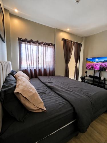 a bedroom with a large bed and a flat screen tv at Staycation by ALCD in San Mateo
