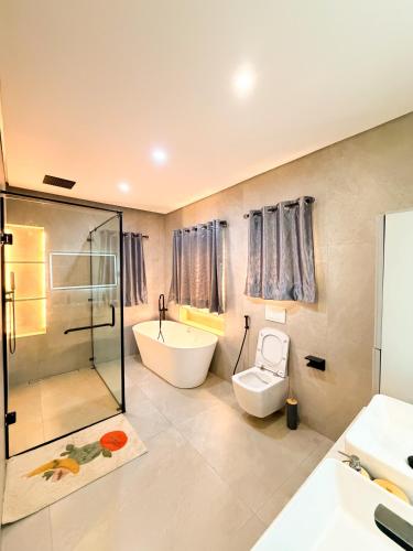a bathroom with a tub and a toilet and a sink at Casa Midelle in Alagbado