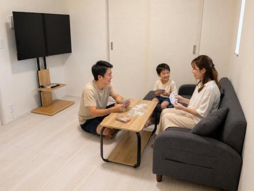 a family sitting in a living room playing a video game at 平宿 本山町ホテル in Kumamoto