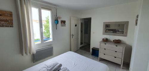a white bedroom with a bed and a window at Villa Belle Ile in Saint-Pierre-dʼOléron