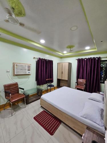 a bedroom with a large bed and two chairs at Arya Palace in Phulabāni
