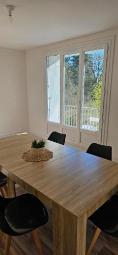 a wooden table with chairs in a room with windows at Appartement T4 proche gare in Guingamp