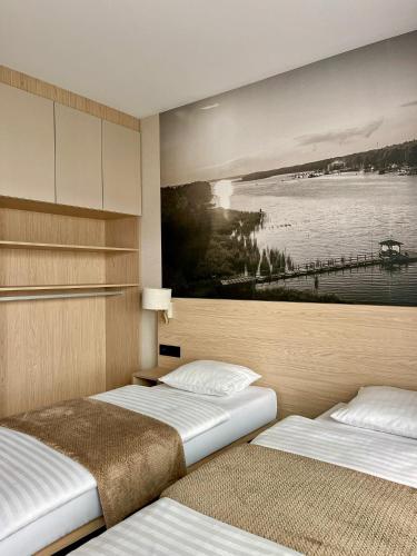 two beds in a room with a painting on the wall at Marina Sława in Sława