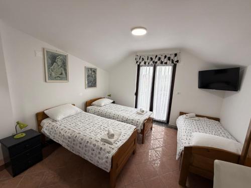 a room with three beds and a flat screen tv at Rooms Vesna in Salopek-Selo