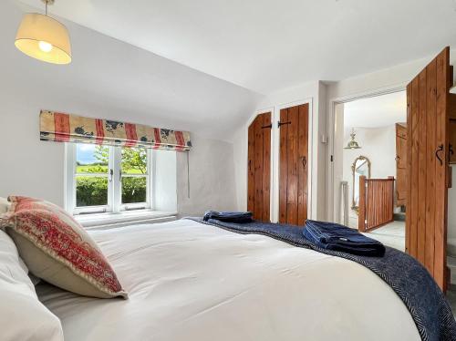 a bedroom with a large white bed with a window at Whitley Farm Molland in Molland