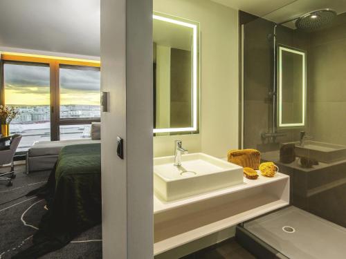 a bathroom with a sink and a bed and a mirror at Novotel Paris Porte Versailles in Paris