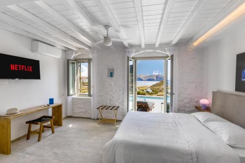 a bedroom with a large white bed and a desk at Villa Evita Panormos private pool & jacouzzi in Mykonos
