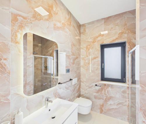 a bathroom with a sink toilet and a mirror at Vila Volme in Banjole