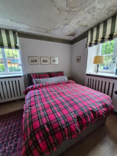 a bedroom with a bed with a plaid blanket at Entzückendes Studio in historischer Villa in Aschau