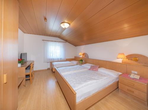 a room with three beds and a desk and a desk at Hotel & Residence Sylvanerhof in Chiusa