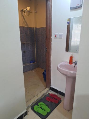 a bathroom with a sink and a shower and two slippers at Humble Homes 1 bedroom Thika Town CBD access to Netflix,Fridge,wifi in Thika