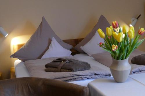 a bed with a vase of flowers on it at Kurbad St Martin in Bad Kohlgrub