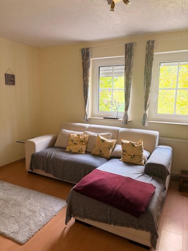 a bedroom with a couch and two windows at Gemütliche 3-Zimmer-Wohnung mit Kupfertalblick in Forchtenberg