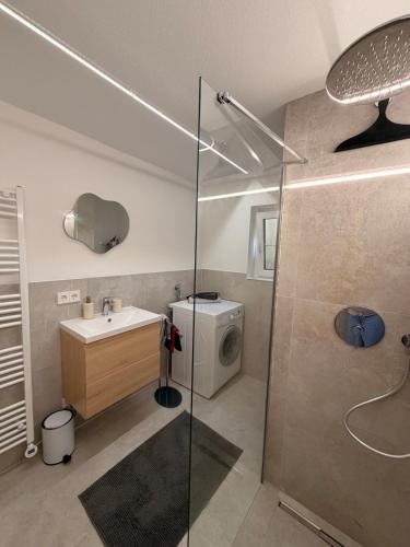a bathroom with a shower and a sink and a washing machine at Gemütliche 3-Zimmer-Wohnung mit Kupfertalblick in Forchtenberg