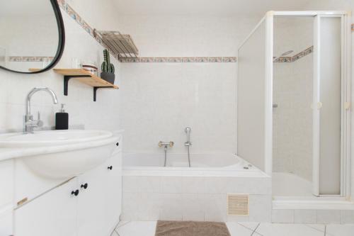 a white bathroom with a tub and a sink at La Villa 103 in Lombez
