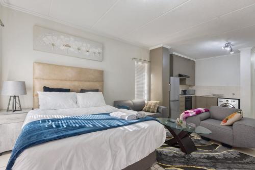 a bedroom with a bed and a living room at Spacious Studio Fourways Sandton - Self Check-in in Sandton