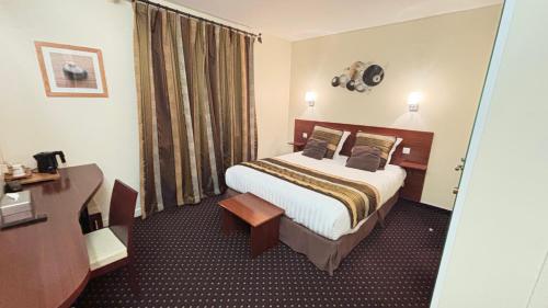 a hotel room with a bed and a desk at Hotel Des Voyageurs in Le Rouget
