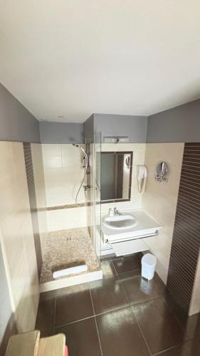 a bathroom with a shower and a sink at Hotel Des Voyageurs in Le Rouget