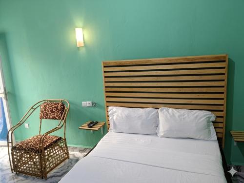 a bedroom with a bed and a chair next to it at Madibak Hotel Limbe in Limbe