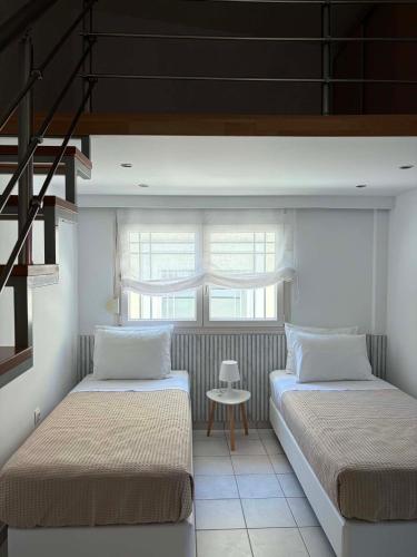 two beds in a room with a window at Armonia Maisonette in Pefkochori