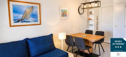 a dining room with a table and a sailboat on the wall at Cap Esterel, quartier Belvédère 2p meublé tourisme 3 étoiles climatisé Rez-de-Jardin, Vue Mer, WIFI, Piscine et Parking inclus in Agay - Saint Raphael