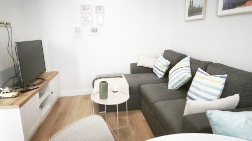 a living room with a gray couch and a table at La Ilusión in Sanxenxo