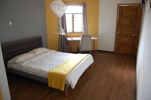 a bedroom with a bed and a desk and a window at Sky Hotels Emali in Mwanda