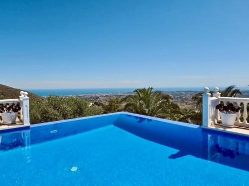 a blue swimming pool with the ocean in the background at Villa Mañana in Mijas