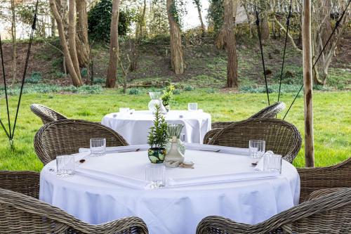 a table with wicker chairs and white tables with flowers at Karels Restaurant Hotel in Braamt