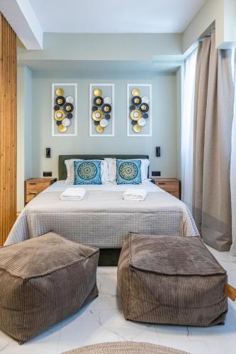 a bedroom with a bed with two ottomans at Ernest Suites Monastiraki in Athens