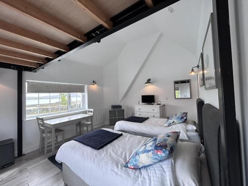 two beds in a room with a table and a desk at Guinness House in Ballyconneely
