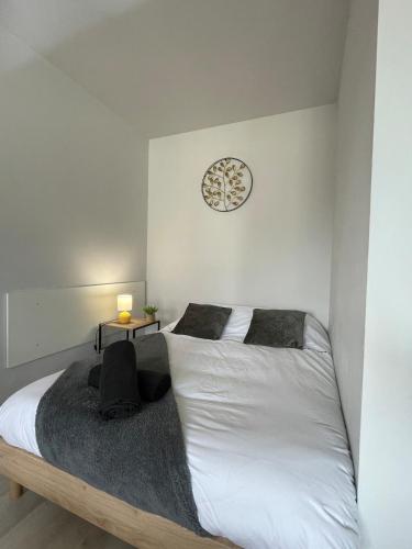 a bedroom with two beds and a clock on the wall at Le Cocon Cornouaillais, hyper centre, parking pv in Quimper