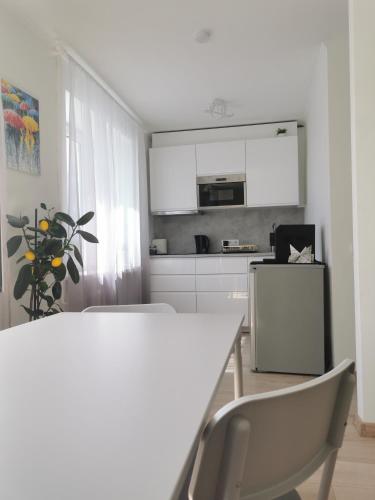 a white kitchen with a white table and chairs at ArSa in Ventspils
