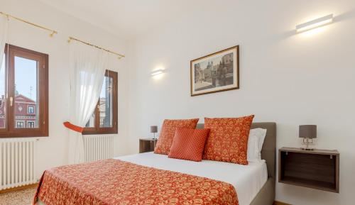 a bedroom with a bed with orange pillows and a window at Residenza Simeon Grande - Luxurious modern apartment in Venice