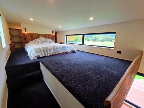 a bedroom with a large bed and a large window at Luxe Tiny Home in Whangarei