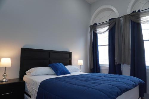a bedroom with a bed with a blue comforter and two windows at New York view 39 in West New York
