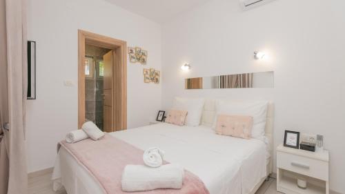 a white bedroom with a large white bed with pink accents at Villa Ivandvor in Split by Villas Guide in Radošić