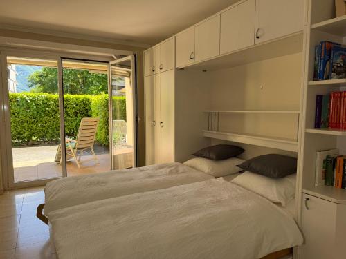 a bedroom with a bed and a balcony with a chair at Residenza delle Fonti by HolAp SA in Minusio