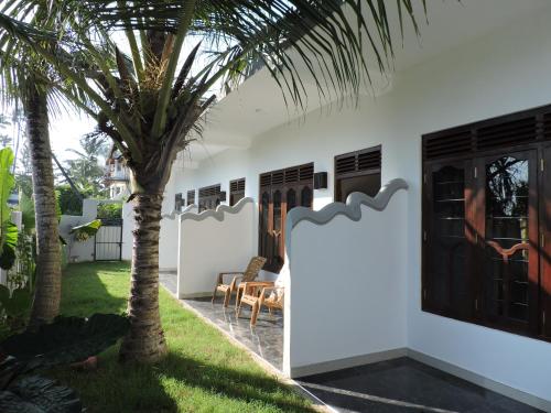 a house with a palm tree in the yard at Seadina Coral Home in Matara